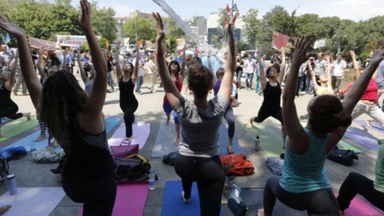 People practice yoga in Gezi Park at Taksim Square in Istanbul June 7, 2013. Istanbul's Gezi Park, yoga practitioners stretch and students read in a makeshift library - a statement of their intent to stay on after a week of protests. At night demonstrators taunt riot police from beyond barricades on the streets around Taksim Square. Those in its Gezi Park hold sit-down protests and discuss Turkey's future.   REUTERS/Osman Orsal (TURKEY - Tags: CIVIL UNREST POLITICS SOCIETY) - RTX10FAH