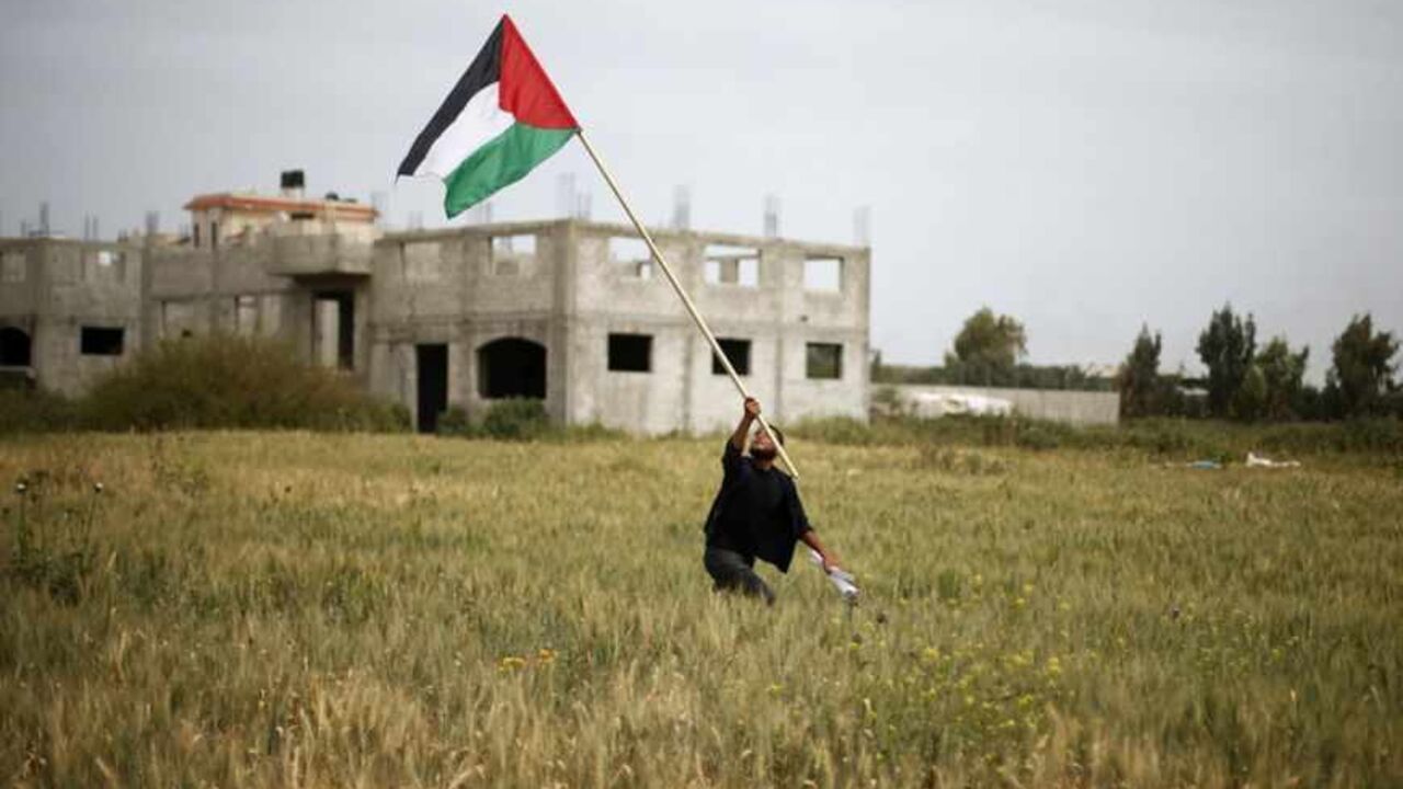 A protester holds a Palestinian flag during a protest marking Land Day in the northern Gaza Strip March 30, 2013. March 30 marks Land Day, the annual commemoration of protests in 1976 against Israel's appropriation of Arab-owned land in the Galilee. REUTERS/Suhaib Salem (GAZA - Tags: POLITICS CIVIL UNREST TPX IMAGES OF THE DAY) - RTXY2PQ