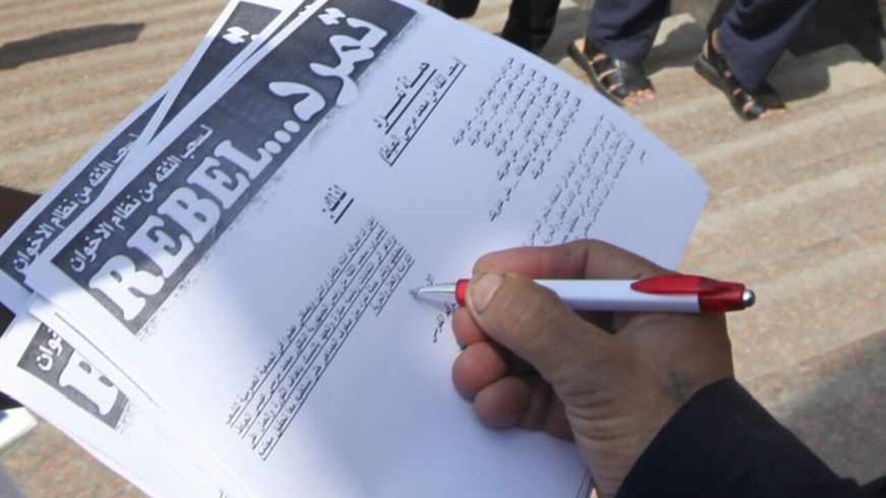 A man signs a "Tamarod" document at Tahrir square in Cairo May 16, 2013. A campaign named "Tamarod", meaning "Rebel", calling for the ouster of Egyptian President Mohamed Mursi and for early presidential elections has gathered over two million signatures since its launch nearly two weeks ago in Egypt, organisers said.      REUTERS/Mohamed Abd El Ghany  (EGYPT - Tags: POLITICS CIVIL UNREST) - RTXZP6G