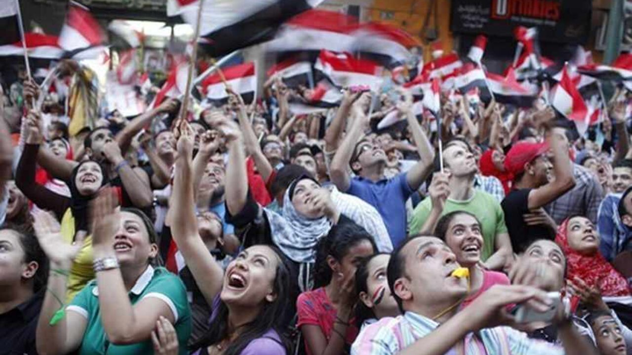 Anti-Mursi protesters look up at a military helicopter over the area as protesters chant slogans at a massive protest for the second day at a main street in Alexandria, July 1, 2013. Egypt's armed forces handed Islamist President Mohamed Mursi a virtual ultimatum to share power on Monday, giving feuding politicians 48 hours to compromise or have the army impose its own roadmap for the country.  REUTERS/Asmaa Waguih (EGYPT - Tags: POLITICS CIVIL UNREST) - RTX1197O