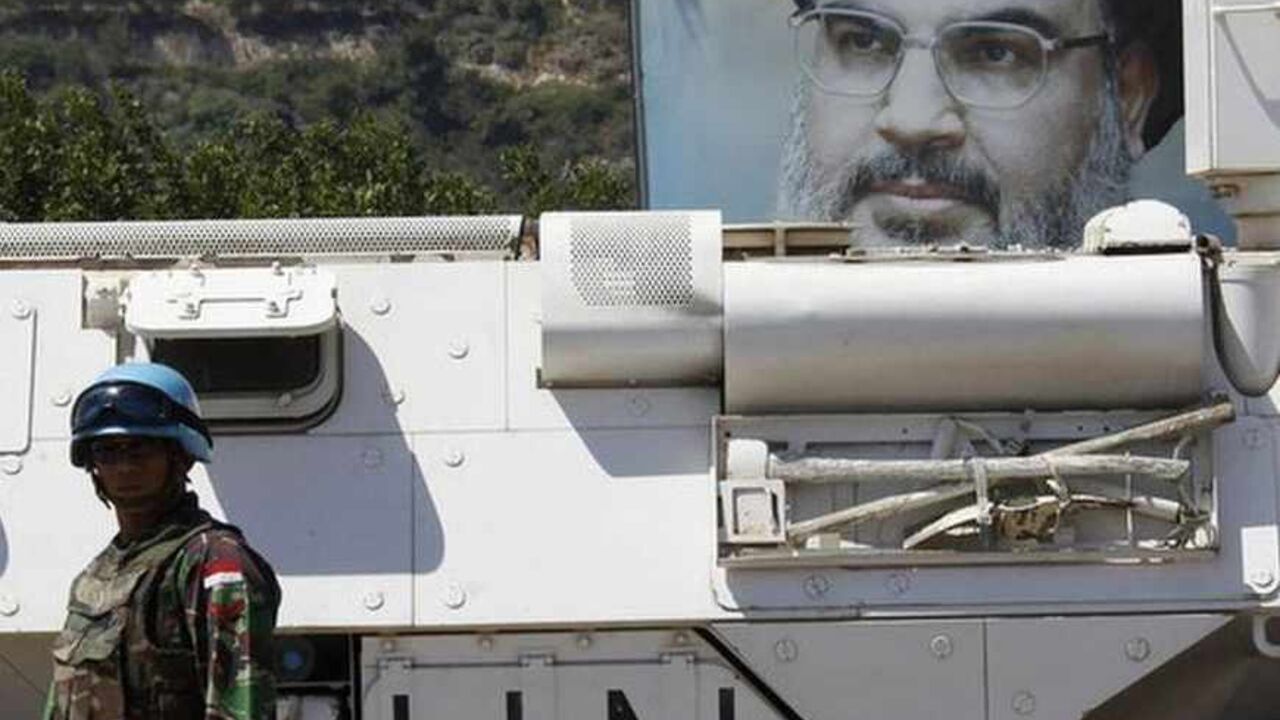 An Indonesian soldier from the United Nations Interim Forces in Lebanon (UNIFIL) stands near a U.N. armoured vehicle as a picture of Lebanon's Hezbollah leader Sayyed Hassan Nasrallah is seen behind him in the southern Lebanese village of Adaisseh July 24, 2013. Europe's decision to blacklist Hezbollah's "military wing" was triggered by the Lebanese movement's growing role in Syria, but the partial ban may have little practical impact due to fears of destabilising Lebanon and the wider Middle East.    REUTE
