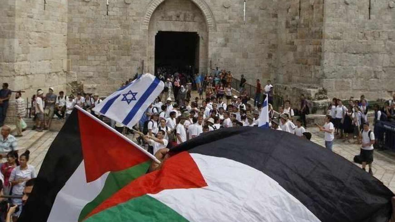 Palestinians wave Palestinian flags as Israeli youths celebrating Jerusalem Day gather in front of the Damascus Gate in Jerusalem's Old City May 8, 2013. Jerusalem Day marks the anniversary of Israel's capture of the Eastern part of the city during the 1967 Middle East War. In 1980, Israel's parliament passed a law declaring united Jerusalem as the national capital, a move never recognised internationally. REUTERS/Ammar Awad (JERUSALEM - Tags: POLITICS ANNIVERSARY) - RTXZEXA