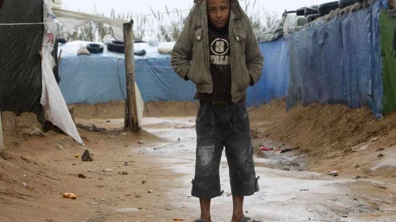 A Syrian refugee boy shields himself from the rain with his jacket at a refugee camp in the city of Tyre in southern Lebanon January 31, 2013. Donor countries have pledged more than $1.5 billion to aid Syrians stricken by civil war, U.N. Secretary-General Ban Ki-moon said on Wednesday after warning that the conflict had wrought a catastrophic humanitarian crisis. REUTERS/Ali Hashisho (LEBANON - Tags: POLITICS CIVIL UNREST TPX IMAGES OF THE DAY) - RTR3D6R0