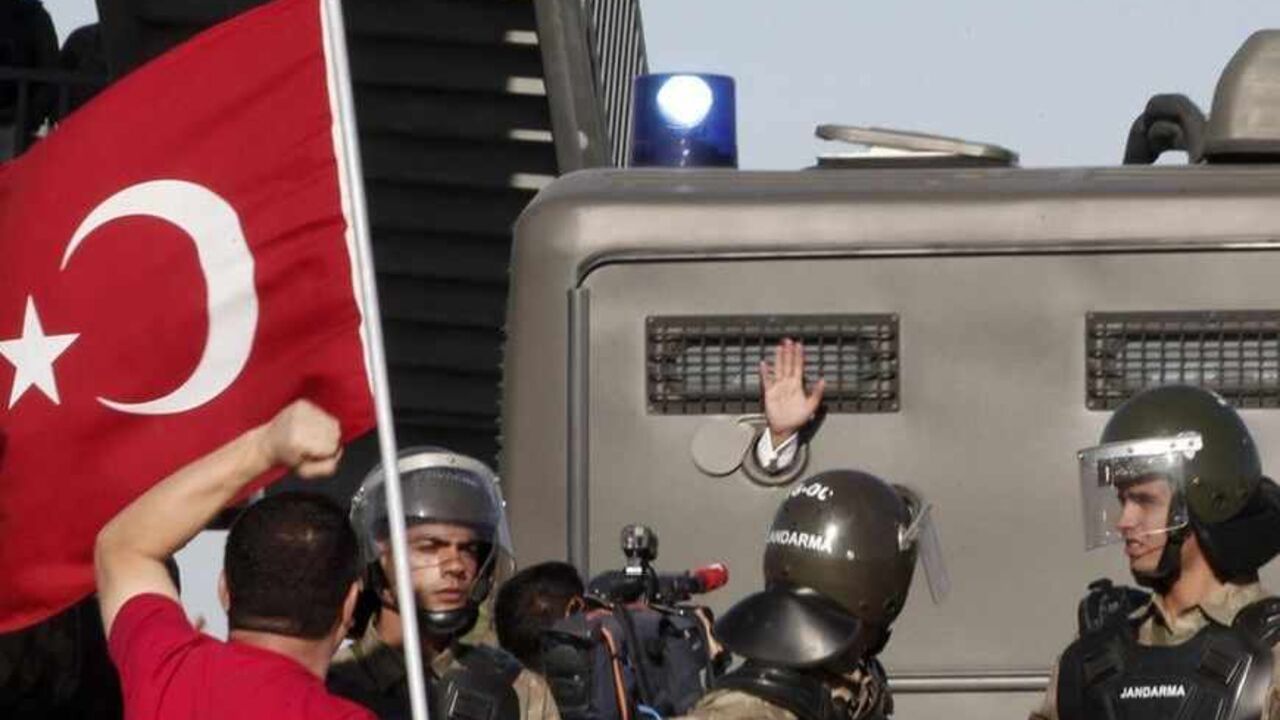 An unidentified defendant waves out of a van as he's driven to a courthouse in Silivri, where a hearing for people charged with attempting to overthrow Prime Minister Tayyip Erdogan's Islamist-rooted government is due to take place, August 5, 2013. A Turkish court on Monday began sentencing nearly 300 defendants accused of plotting to overthrow the government, handing prison sentences of up to 20 years to some and acquitting 21 others. The court was announcing the verdicts individually. Verdicts on high-pro