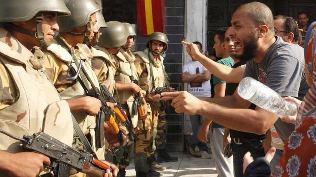 Supporters of ousted Egyptian President Mohamed Mursi argue with riot police and army personnel during clashes near Rabaa Adawiya square in Cairo August 14, 2013. Egypt is in turmoil after security forces moved in to clear the protest camps of thousands of supporters of deposed Islamist president Mohamed Mursi on Wednesday, and violence spread around the country. Protesters clashed with police and troops who used bulldozers, teargas and live ammunition to clear two Cairo sit-ins. Egypt's health ministry say