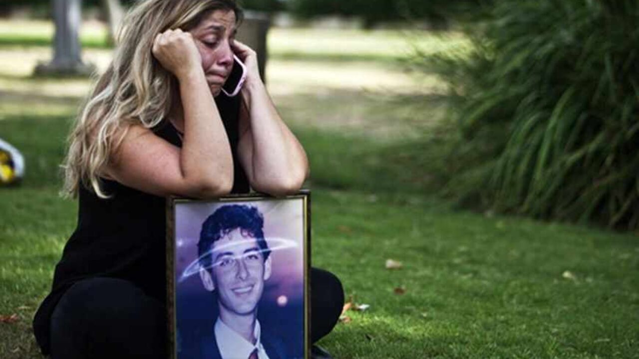Gila Molcho, sister of Ian Feinberg, who was killed in 1993 by Palestinians in the Gaza Strip, speaks on the phone while holding a framed portrait of Feinberg, during a protest against the government's plan to free Palestinian prisoners, in Tel Aviv August 12, 2013. Israel on Monday named 26 Palestinian prisoners, one of them convicted of killing Feinberg, to be freed this week under a deal enabling U.S.-backed peace talks to resume, although Palestinians said these had been undermined by newly announced pl