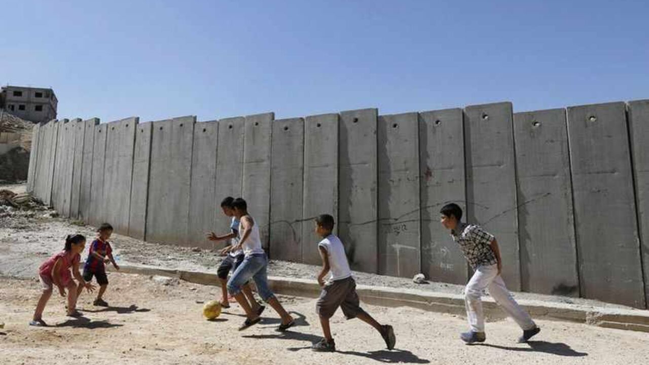 Palestinian children play near a section of the controversial Israeli barrier in Shuafat refugee camp in the West Bank near Jerusalem July 29, 2013. Israeli and Palestinian officials put forward clashing formats for peace talks due to resume in Washington on Monday for the first time in nearly three years after intense U.S. mediation. It is unclear how the United States hopes to bridge the core issues in the dispute, including borders, the future of Jewish settlements on the West Bank, the fate of Palestini