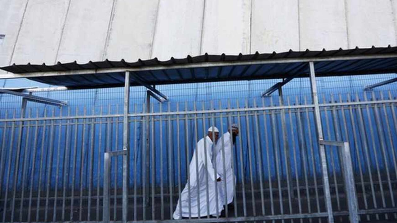 Palestinians walk near the controversial Israeli barrier as they cross into Jerusalem at an Israeli checkpoint in the West Bank town of Bethlehem July 26, 2013. Israeli and Palestinian officials put forward clashing formats for peace talks due to resume in Washington on Monday for the first time in nearly three years after intense U.S. mediation. It is unclear how the United States hopes to bridge the core issues in the dispute, including borders, the future of Jewish settlements on the West Bank, the fate 
