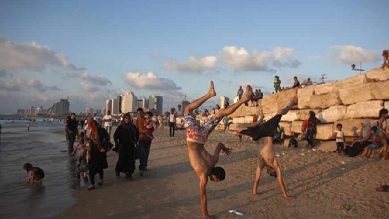 Palestinians play at the seaside of the Mediterranean at a beach in Tel Aviv during Eid al-Fitr, which marks the end of the holy month of Ramadan August 11, 2013. The Israeli Coordinator for Government Activities in the Territories' (COGAT) responsible for implementing Israel's civilian policy in the occupied West Bank and Gaza Strip, eased permit restrictions for thousands of Palestinians wanting to enter Israel following a security assessment, allowing many to enjoy the beaches along Israel's Mediterranea