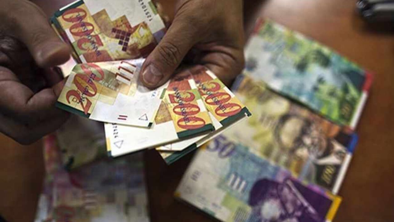 A bank employee counts Israeli Shekel notes for the camera at a bank branch in Tel Aviv August 7, 2013. Picture taken August 7, 2013. REUTERS/Nir Elias (ISRAEL - Tags: BUSINESS) - RTX12EW0