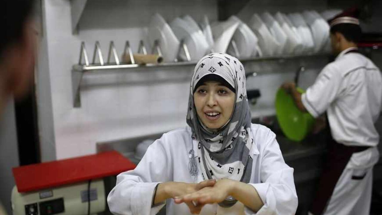 A hearing impaired employee uses sign language to communicate with a co-worker in the kitchen of Atfaluna restaurant in Gaza City October 17, 2012. The restaurant run and staffed by deaf people opened for business in the Gaza Strip on Tuesday, helped by Palestinians seeking to build a more inclusive society where people with disabilities can realise their full potential. Picture taken October 17, 2012. REUTERS/Suhaib Salem (GAZA - Tags: FOOD SOCIETY) - RTR39A69