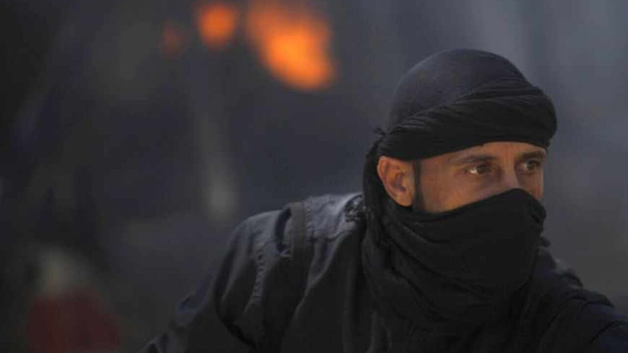 A fighter from the Islamist Syrian rebel group Jabhat al-Nusra is seen in front of a burning vehicle, caused by what activists said were missiles fired by a Syrian Air Force fighter jet from forces loyal to Syria's President Bashar al-Assad, at their base in Raqqa province, east Syria, May 12, 2013. REUTERS/Hamid Khatib (SYRIA - Tags: CONFLICT POLITICS CIVIL UNREST) - RTXZJTP