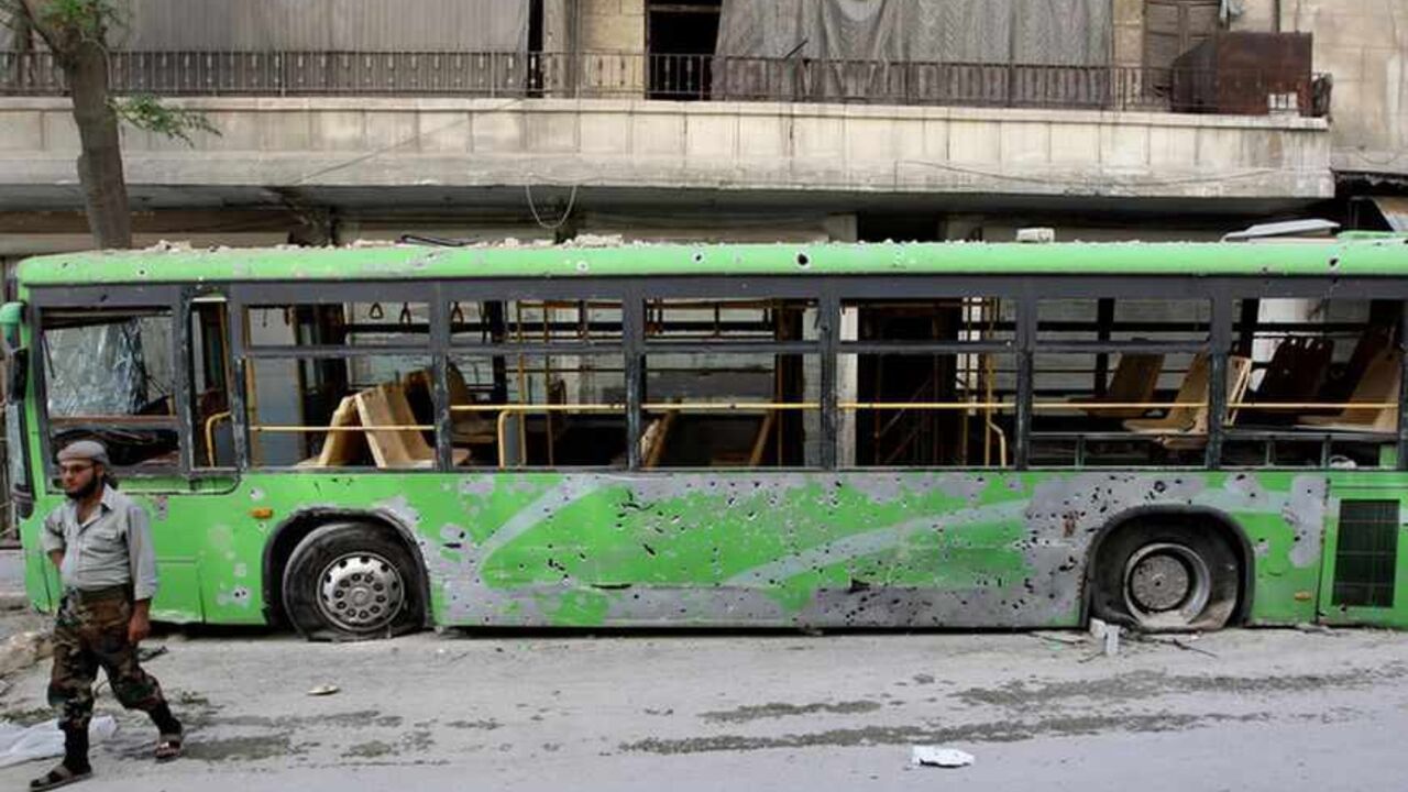 A member of the Free Syrian Army walks past a damaged bus in Aleppo's Karm al-Jabal district, June 3, 2013. REUTERS/Muzaffar Salman (SYRIA - Tags: CONFLICT POLITICS) - RTX10ALJ