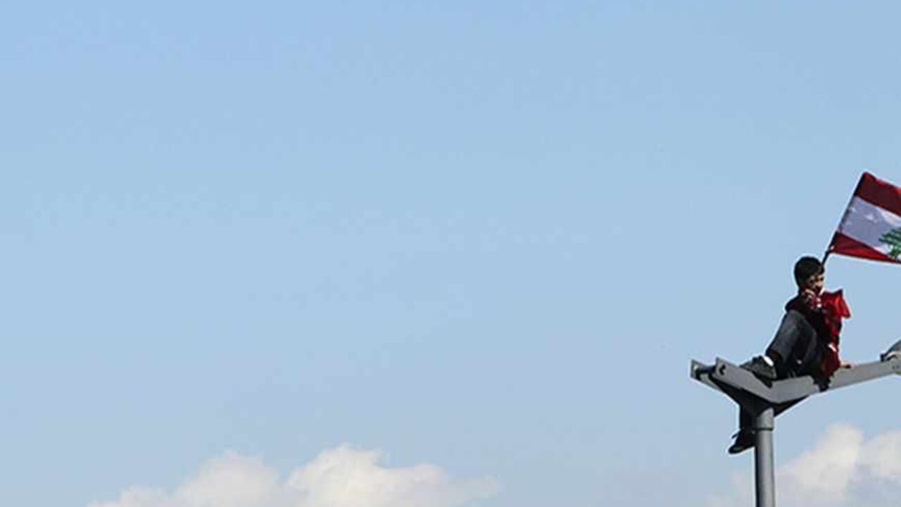 A supporter of Lebanon's toppled premier Saad al-Hariri waves a flag atop a lamp post during a rally in Martyrs' Square in Beirut March 13, 2011. Tens of thousands of supporters of Lebanon's toppled premier Saad al-Hariri rallied in Beirut on Sunday, calling for the Shi'ite group Hezbollah which ousted him to put its weapons under state control. REUTERS/Mohamed Azakir  (LEBANON - Tags: CIVIL UNREST POLITICS) - RTR2JUHF