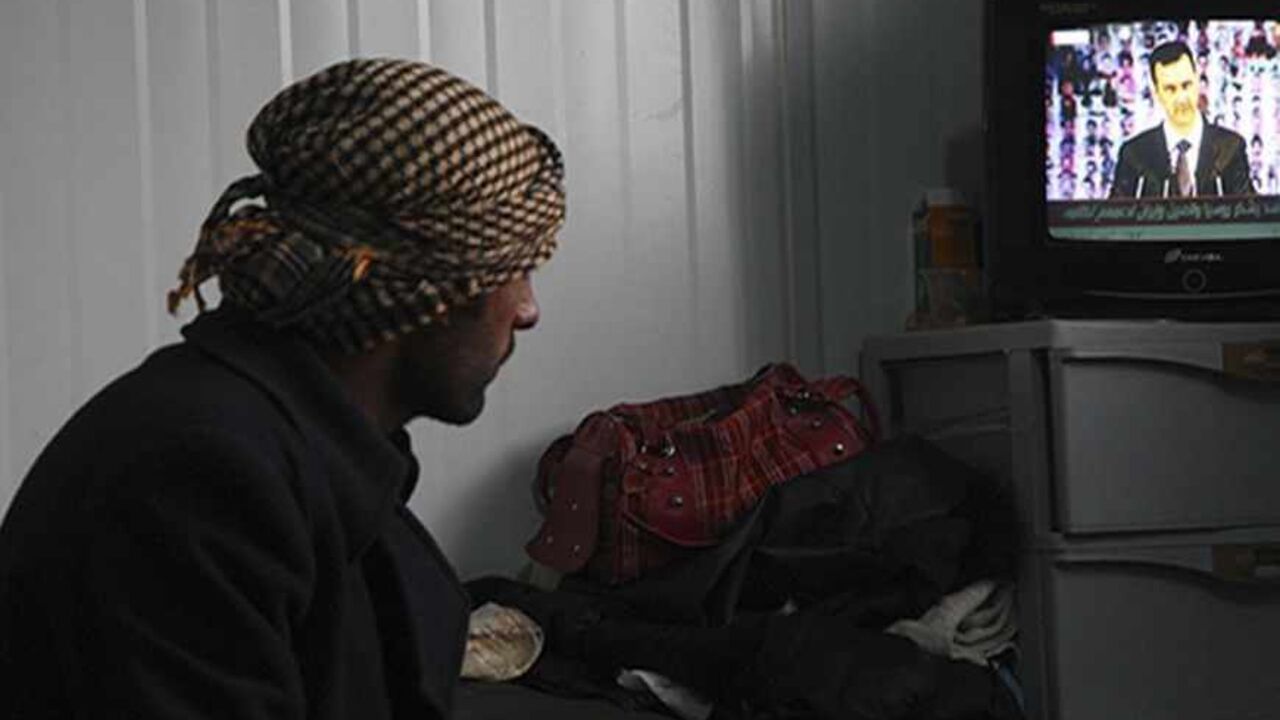 A Syrian refugee watches a television broadcast of Syria's President Bashar al-Assad speaking in Damascus, in their container at the Al-Zaatari refugee camp in the Jordanian city of Mafraq, near the border with Syria, January 6, 2013. Assad made his first public appearance in months on Sunday, calling for a "full national mobilisation" to fight against rebels he described as al Qaeda terrorists.      REUTERS/Majed Jaber (JORDAN - Tags: POLITICS CIVIL UNREST) - RTR3C5EE