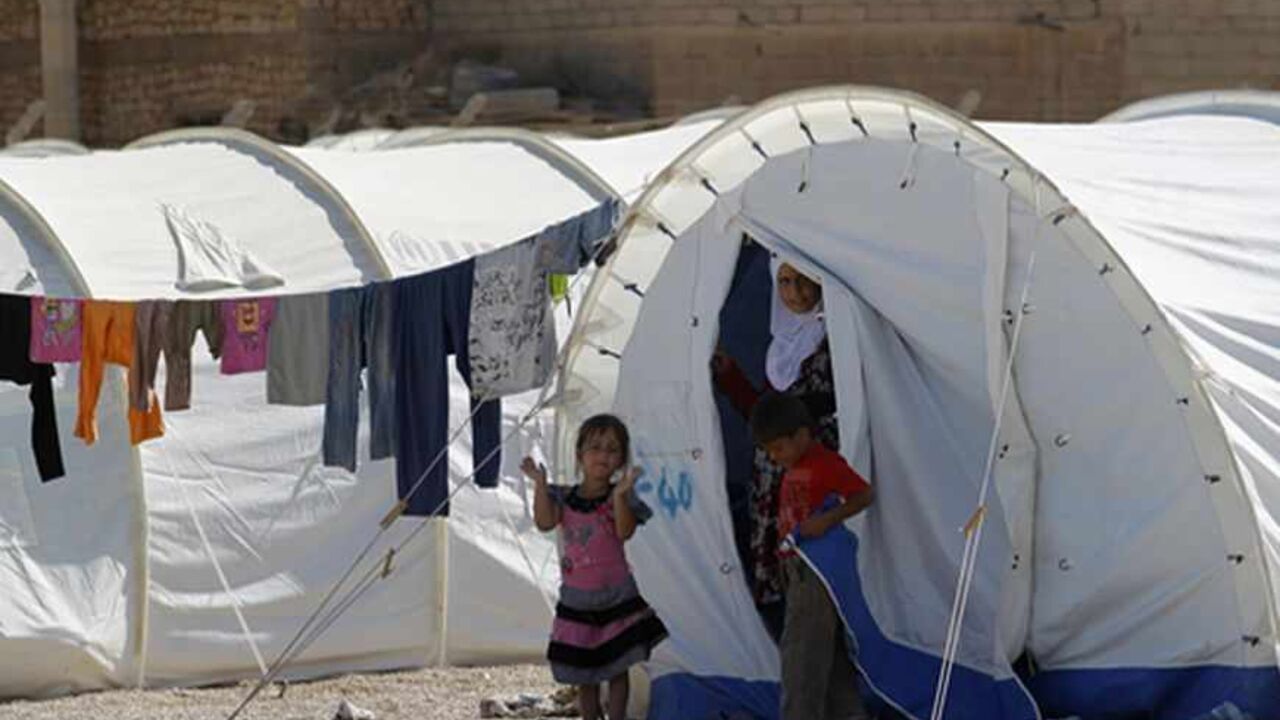 Syrian refugees look out from their tent at a refugee camp in al-Qaim, Anbar province, September 8, 2012. Al Qaim, in the Sunni heartland of Anbar province, reflects the tricky balancing act Iraq's Shi'ite leaders face in Syria, whose crisis is testing the Middle East's sectarian divide. Al Qaim and its neighbouring Syrian counterpart Albu Kamal are on a strategic supply route for smugglers, gun-runners and now insurgents aiming to join the rebellion. Picture taken September 8, 2012. To match Feature SYRIA-