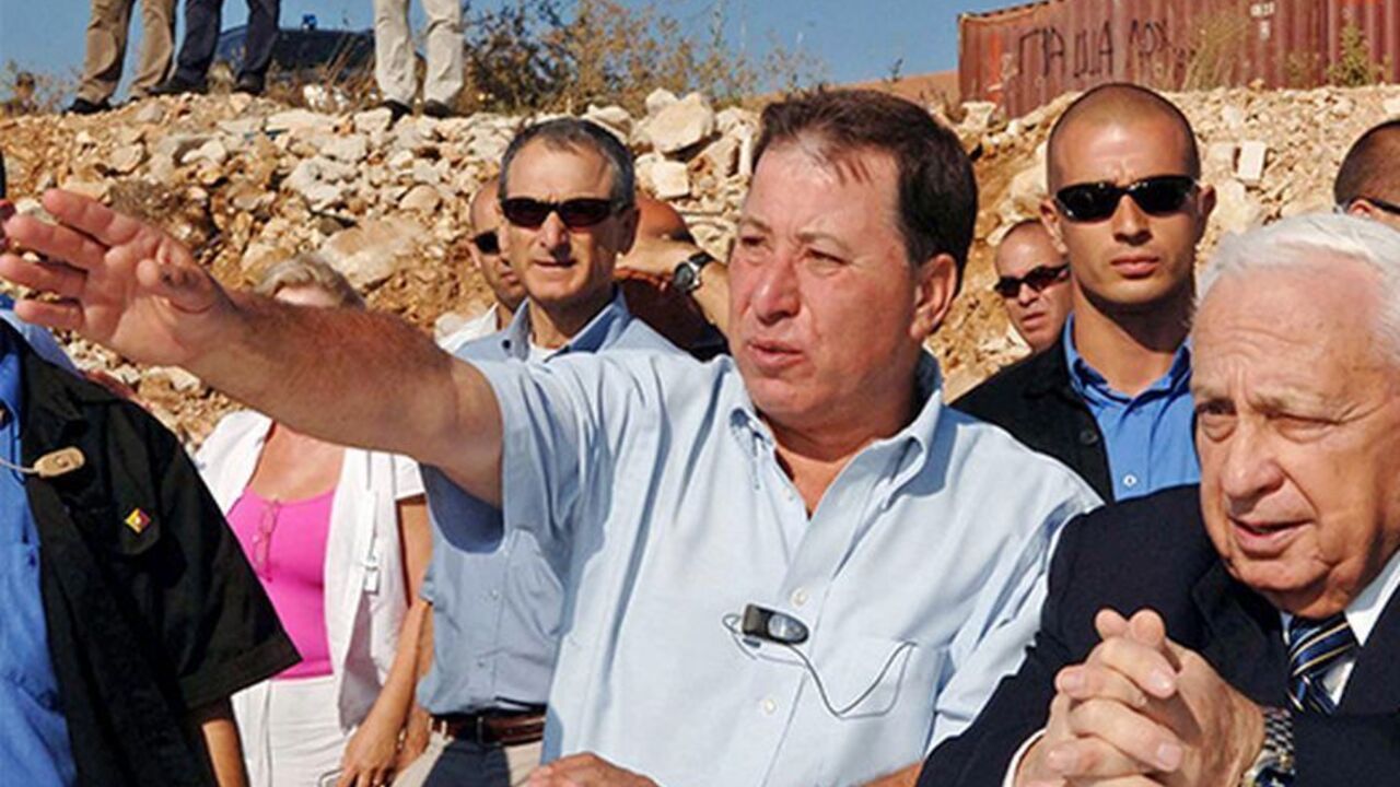 Israeli Prime Minister Ariel Sharon (R) listens to Mayor Ron Nachman (L) during his visit to the West Bank settlement of Ariel July 21, 2005 in this picture released by the Israeli Government Press Office. Sharon's deputy raised the prospect on Thursday of bringing forward the start of Israel's withdrawal from Gaza to prevent opponents of the pullout from carrying out threats to disrupt it. ISRAEL OUT  REUTERS/Moshe Milner/GPO/Handout - RTRI949