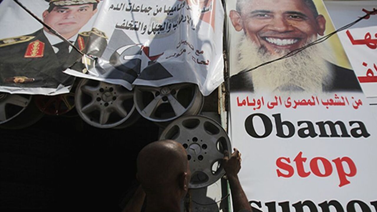 Salah Abdel Moneim, 40, an anti-Mursi supporter of Egypt's army works at his shop with poster of Egypt's army chief General Abdel Fattah al-Sisi (L) and a poster depicting U.S. president Barack Obama with a beard (R) in downtown Cairo August 7, 2013. Egypt's presidency said on Wednesday that diplomatic efforts to end the country's political turmoil had failed and warned that the Muslim Brotherhood of ousted President Mohamed Mursi would be held responsible for the consequences. In a statement, interim Presi