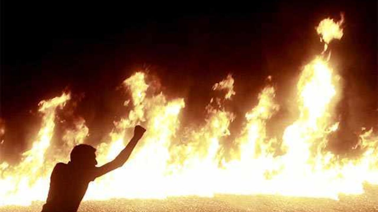 A protester stands near a line of fire during a demonstration in Cairo October 9, 2011. Nineteen people were killed in Cairo on Sunday when Christians, some carrying crosses and pictures of Jesus, clashed with military police, medical and security sources said, in the latest sectarian flare-up in a country in political turmoil. REUTERS/Amr Abdallah Dalsh  (EGYPT - Tags: CIVIL UNREST POLITICS RELIGION TPX IMAGES OF THE DAY) - RTR2SGGO