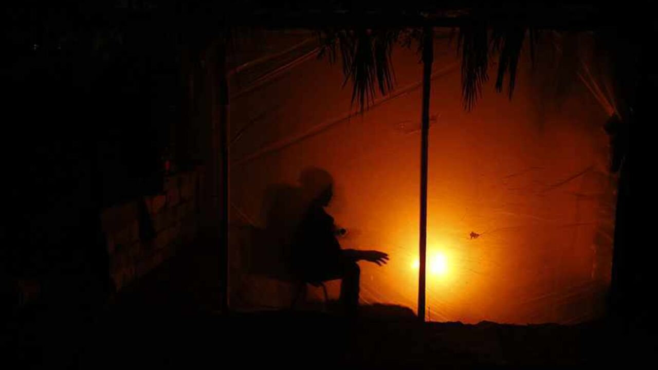 A Palestinian man warms himself by a fire inside his makeshift shelter during a power cut in the northern Gaza Strip November 11, 2013. Gaza's lone power plant shut its generators on November 1, 2013 due to a fuel shortage, a move that will likely increase already long blackout hours in the impoverished coastal territory run by the Islamist Hamas group. Power has been provided to different areas in the territory in six-hour shifts since the closure. REUTERS/Mohammed Salem (GAZA - Tags: ENERGY) - RTX159HC