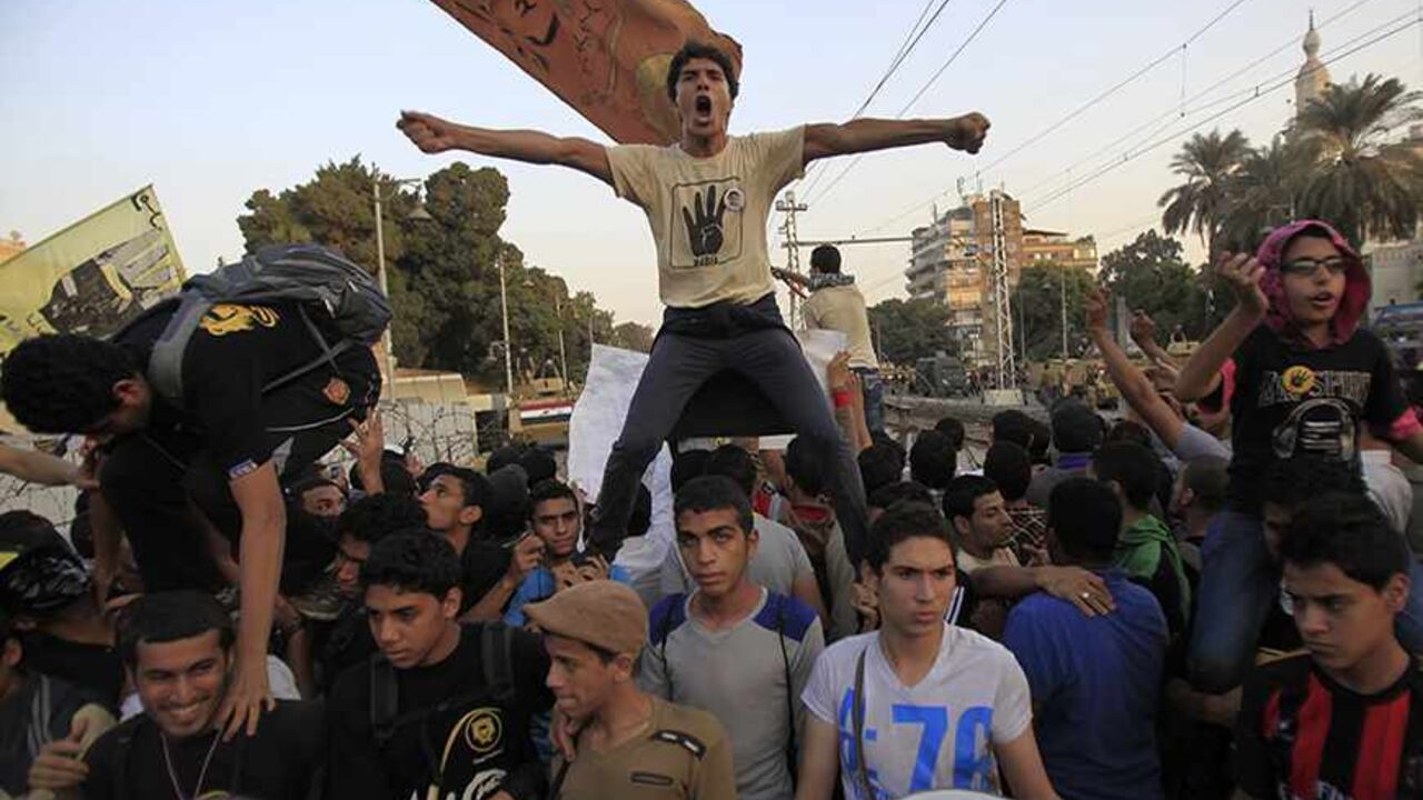 Supporters of the Muslim Brotherhood and ousted Egyptian President Mohamed Mursi shout slogans against the military and interior ministry, during a protest in front of barbed wire, army soldiers and the riot police at El-Thadiya presidential palace in Cairo, November 15, 2013. Supporters of ousted Egyptian President Mohamed Mursi staged one of their largest protest marches in weeks on Friday, a day after Egypt's military-backed government lifted a three month state of emergency.Thousands of demonstrators ma