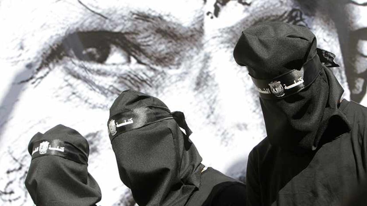 Masked Palestinian Fatah supporters stand in front of a poster depicting late Palestinian leader Yasser Arafat during a rally marking the 9th anniversary of his death at al-Najah University campus in the West Bank city of Nablus November 10, 2013. REUTERS/Abed Omar Qusini (WEST BANK - Tags: POLITICS ANNIVERSARY) - RTX157QB