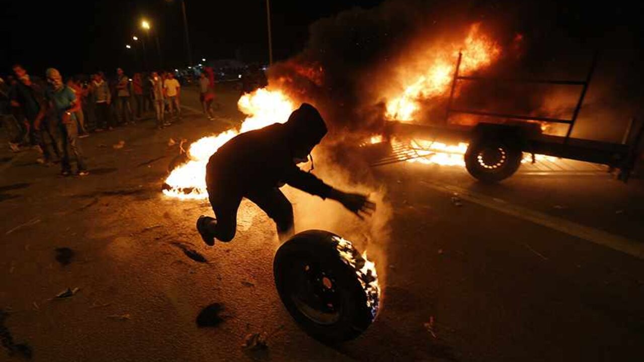 A protester rolls a burning tyre towards Israeli police during a demonstration showing solidarity with Bedouin Arabs who are against a government displacement plan for Bedouins in the Southern Negev desert in the village of Hura in southern Israel November 30, 2013. REUTERS/Baz Ratner  (ISRAEL - Tags: CIVIL UNREST POLITICS TPX IMAGES OF THE DAY) - RTX15YV8