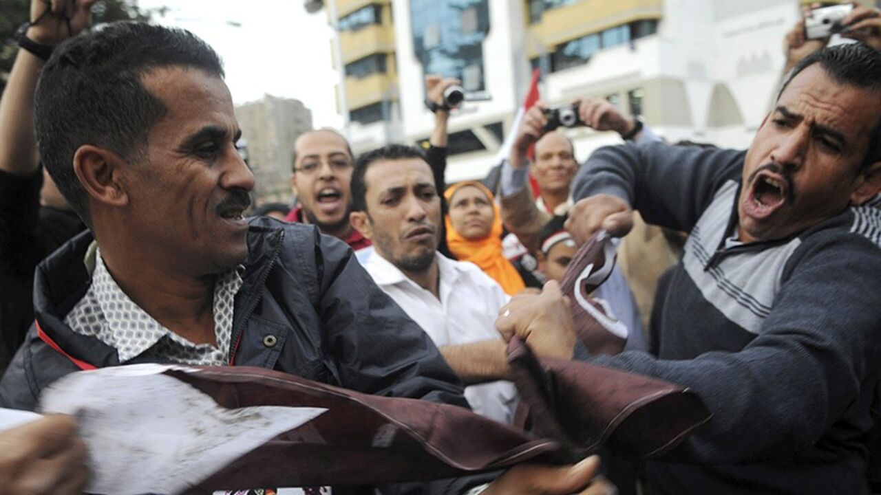Egyptians cut a Qatari flag during a protest against what they say is Qatar's backing of ousted Egyptian president Mohamed Mursi's government, outside the Qatari Embassy in Cairo November 30, 2013. REUTERS/Stringer (EGYPT - Tags: POLITICS CIVIL UNREST) - RTX15Z60