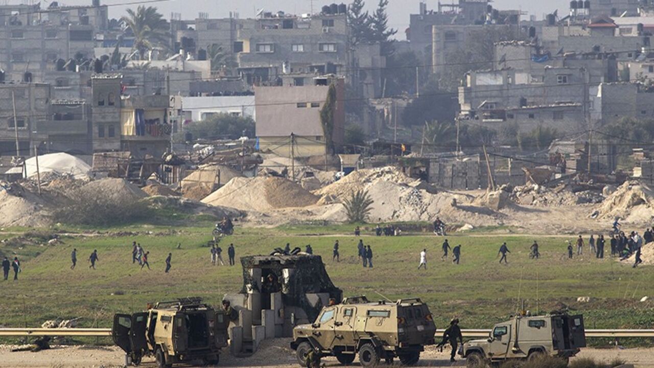 Palestinian demonstrators protest near the Israeli border fence with Gaza, as Israeli soldiers stand guard on the other side near Karni crossing, January 17, 2014. REUTERS/Amir Cohen  (ISRAEL - Tags: MILITARY CIVIL UNREST RELIGION POLITICS) - RTX17IF1