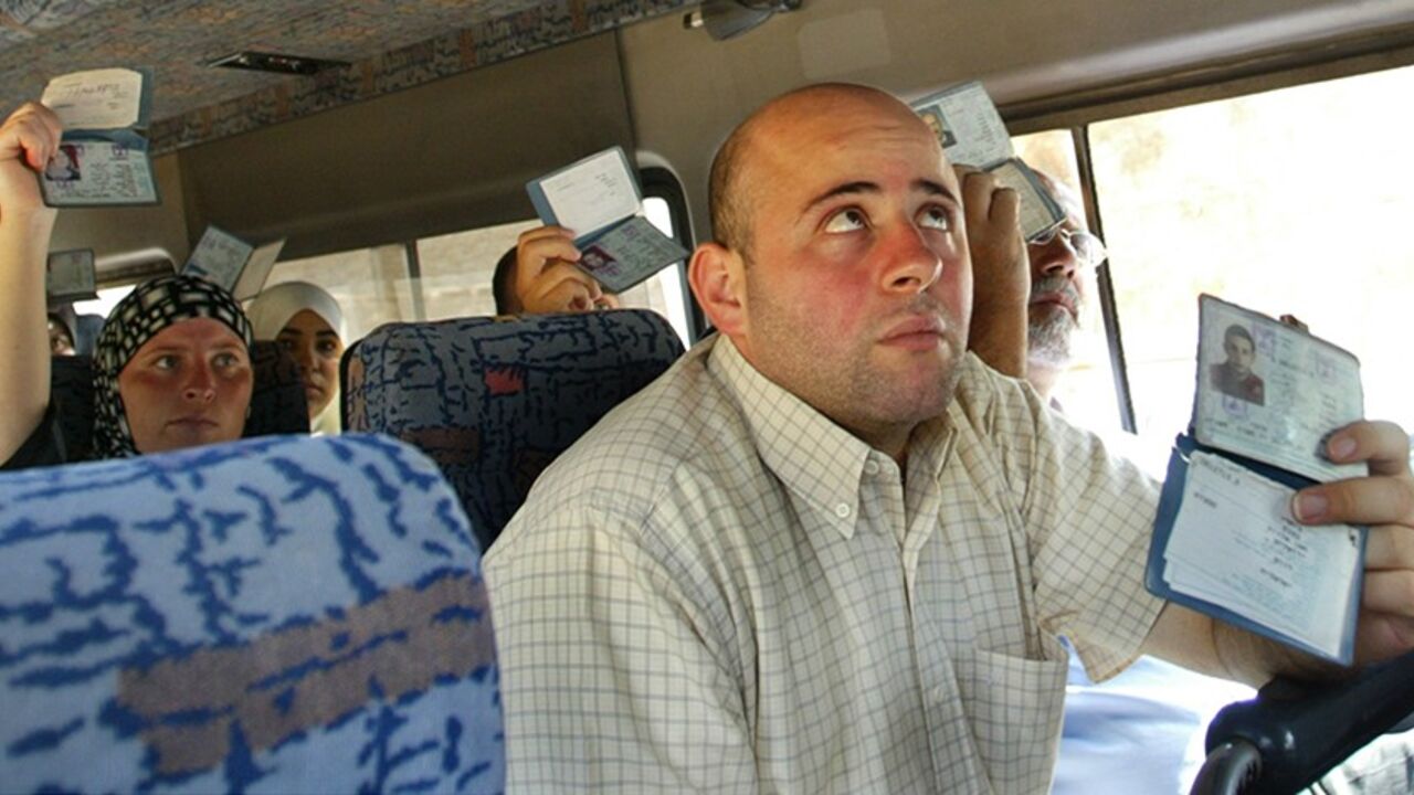 Palestinians show their ID cards to Israeli police inside a bus in Jerusalem August 12, 2004. Investigators were still examining if members of a militant cell which bombed a West Bank checkpoint Wednesday were still at large. The blast killed two Palestinians and wounded 16 people. REUTERS/Gil Cohen Magen  GCM/SM - RTR8GY0
