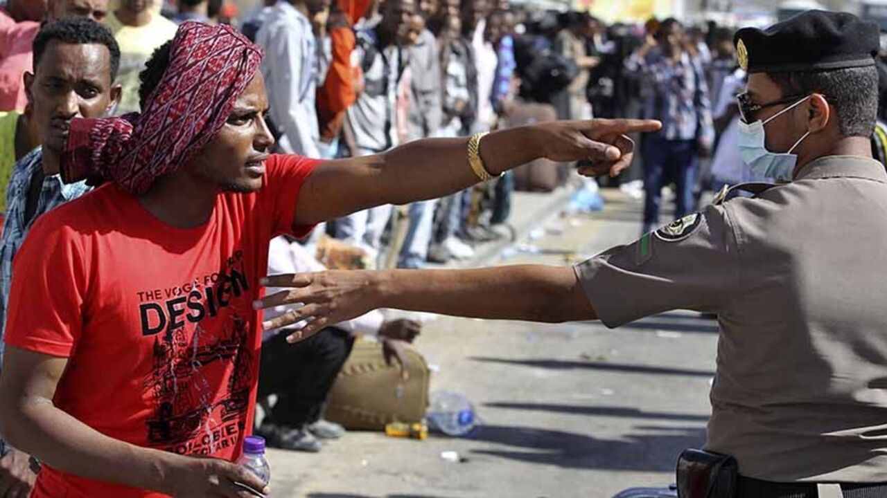 An Ethiopian worker argues with a member of the Saudi security forces as he waits with his countrymen to be repatriated in Manfouha, southern Riyadh, November 11, 2013. Thousands of mostly African workers gathered in Riyadh on Sunday seeking repatriation after two people were killed in overnight rioting that followed a visa crackdown by Saudi authorities. One of those killed was a Saudi, said a government statement, and the other was not identified. An Ethiopian man was killed in a visa raid last week. Ethi