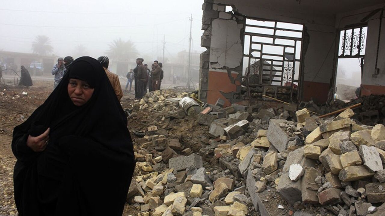 A woman walks past the site of a bomb attack in Balad Ruz, in northeastern Iraq, January 3, 2014. A suicide bomber driving a car packed with explosives killed at least 12 people who had gathered to buy and sell cars in Iraq on Thursday, local officials said. No group immediately claimed responsibility for the attack, which took place near the car markets in the town of Balad Ruz, in northeastern Iraq, injuring another 25 people.   REUTERS/Mohammed Adnan (IRAQ - Tags: CIVIL UNREST) - RTX170P9