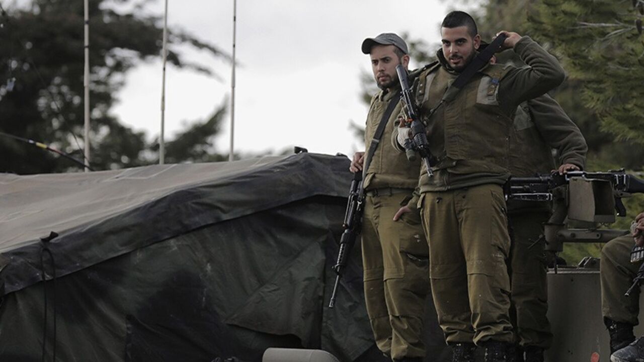 Israeli soldiers stand atop an armoured personnel carrier (APC) positioned near the Lebanese border, close to the northern Israeli town of Shlomi February 27, 2014. Israel's northern region near Lebanon was tense on Thursday and the military ordered farmers away from fields abutting the border, a day after the Lebanese Hezbollah militia threatened to respond to an Israeli air strike that hit one of its bases on the border with Syria earlier in the week. REUTERS/Ammar Awad (ISRAEL - Tags: MILITARY POLITICS) 