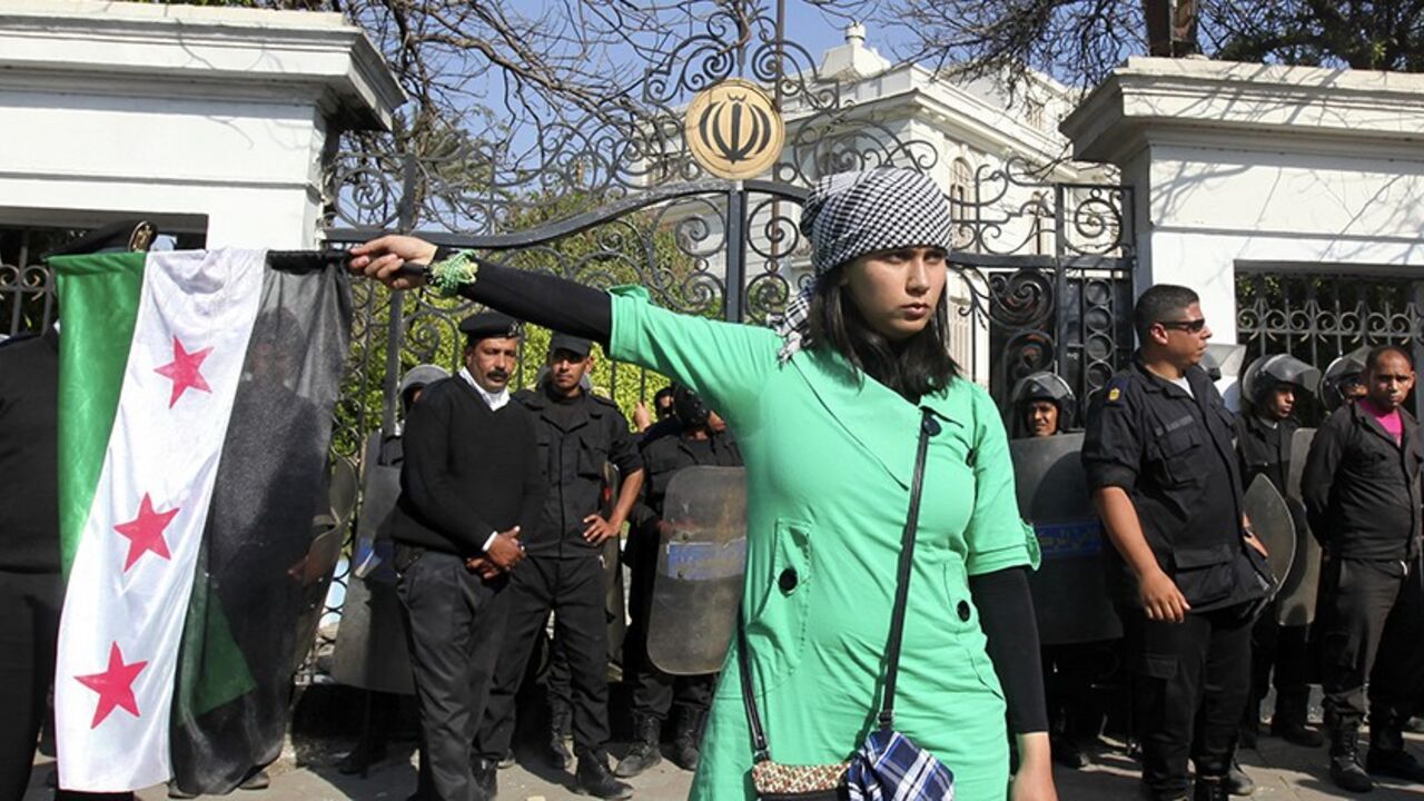 A protester holds the Syrian revolutionary flag in front of police standing guard outside the Iranian ambassador's house during a protest against Iran in Cairo April 5, 2013. Ultra-Conservative Islamist Salafists brought down the Iranian flag at the house of the Iranian ambassador in Egypt Mojtaba Amani on Friday, and replaced it with the Syrian revolutionary flag. REUTERS/Mohamed Abd El Ghany (EGYPT - Tags: POLITICS CIVIL UNREST) - RTXY9MP