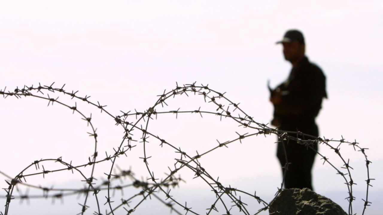 MIRJAVEH, IRAN:  An Iranian soldier stands guard on a mound built to prevent drug trafficking 02 December 2003 in the Mirjaveh point where the borders of Iran, Afghanistan and Pakistan meet. But despite the bulldozed trenches and mounds of dust and the string of machine-gun posts ought to be enough to put off all but the most suicidal drug traffickers hoping to enter Iran, officials taking the UN anti-drugs tsar on the tour admitted they were losing the war on drugs.     AFP PHOTO/Behrouz MEHRI   (Photo cre