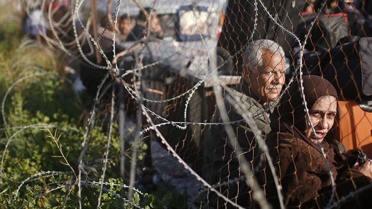 Palestinians hoping to cross into Egypt wait behind a barbed wire fence at the Rafah crossing between Egypt and the southern Gaza Strip March 29, 2014. Egyptian authorities partially reopened Rafah border crossing, Gaza's main window to the world, on Saturday for three days after 50 days of its closure, Palestinian border officials said. Since the overthrow of Egyptian President Mohamed Mursi in July 2013, the authorities have largely kept the crossing closed, only opening it partially for limited periods o
