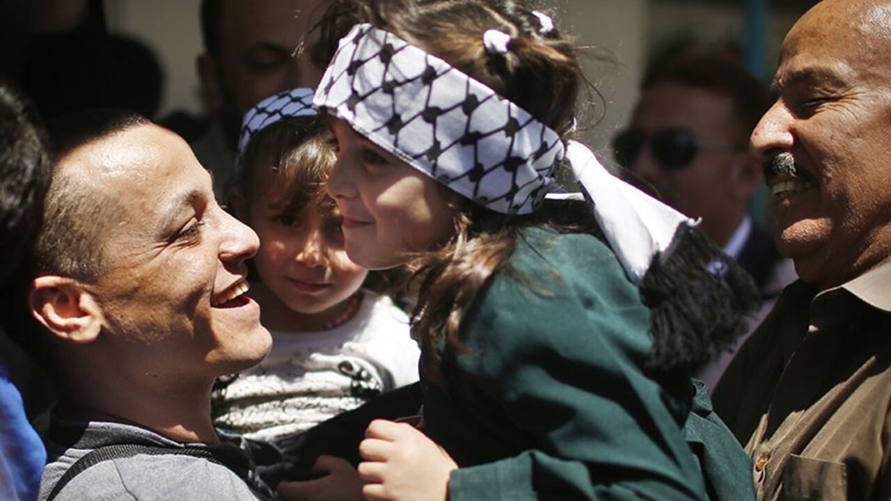 A Palestinian Fatah member holds his daughter after his release from a Hamas-run prison in Gaza City April 21, 2014. Hamas-run ministry of interior in Gaza freed 10 prisoners of the rival Fatah movement of President Mahmoud Abbas on Monday, calling it a gesture for achieving the Palestinian reconciliation. REUTERS/Suhaib Salem (GAZA - Tags: POLITICS) - RTR3M1T6