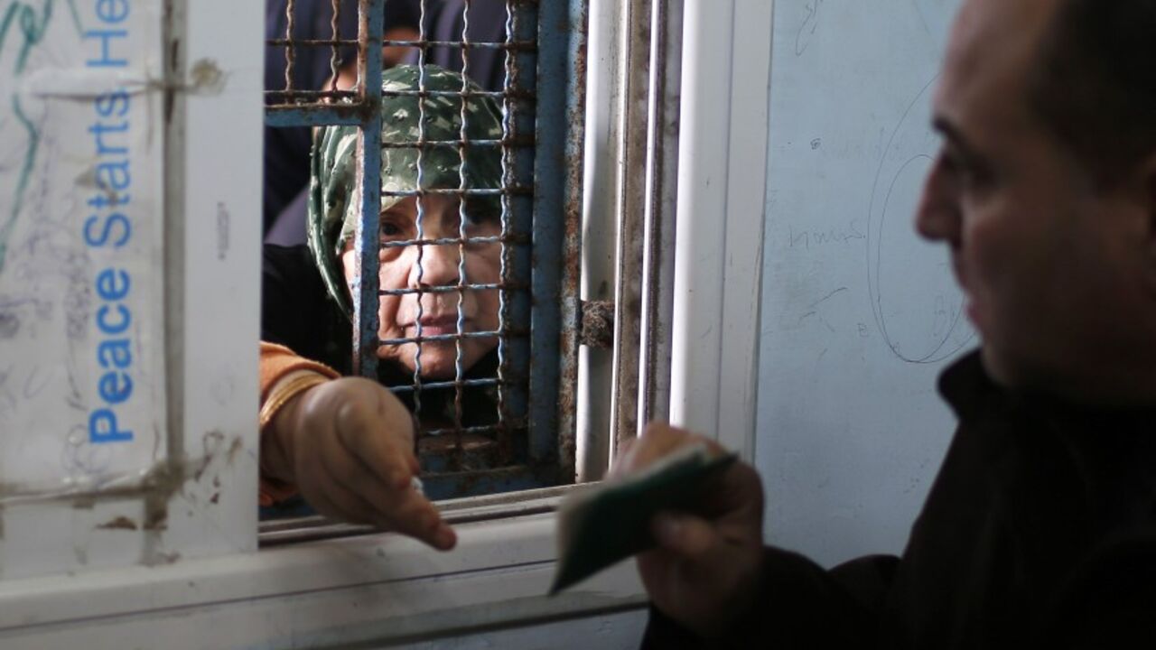 A Palestinian woman presents her identification as she waits to receive food supplies from a United Nations food distribution centre in Gaza City December 19, 2013. Almost a million people are expected to need food aid in the Gaza Strip next year, a U.N. agency said on Wednesday as it appealed for $95 million from donors. REUTERS/Mohammed Salem (GAZA - Tags: POLITICS SOCIETY) - RTX16O8Y