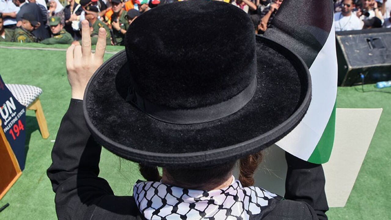A member of Neturei Karta, a small faction of ultra-Orthodox Jews who oppose Israel's existence, waves a Palestinian flag to express support for the Palestinian bid for statehood recognition at the United Nations as thousands of Palestinians attend a demonstration on September 21, 2011 in the West Bank city of Nablus. Palestinians are preparing to submit a formal request to become the 194th member of the United Nations when the General Assembly begins its meetings on September 20, despite US and Israeli opp