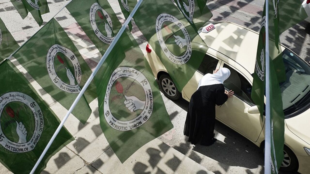 A woman hails a taxi while standing under Patriotic Union of Kurdistan (PUK) logos before Iraq's parliamentary elections in Sulaimaniya April 28, 2014. Picture taken April 28, 2014.        To match IRAQ-ELECTION/KURDS      REUTERS/Jacob Russell (IRAQ - Tags: ELECTIONS POLITICS) - RTR3N0GY