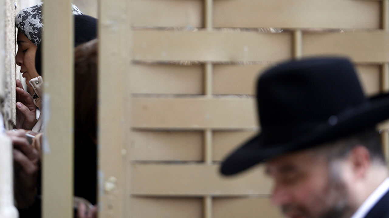 A woman prays on one side of a partition at the Western Wall in Jerusalem's Old City February 11, 2013. Israeli police detained 10 women at one of Judaism's most sacred sites on Monday for wearing prayer shawls, which Orthodox tradition sees as solely for men, a spokesman said.The incident at the Western Wall highlighted the divisions between the more liberal streams of Judaism and politically powerful Orthodox groups that traditionally limit the role of women in prayer. REUTERS/Baz Ratner (JERUSALEM - Tags