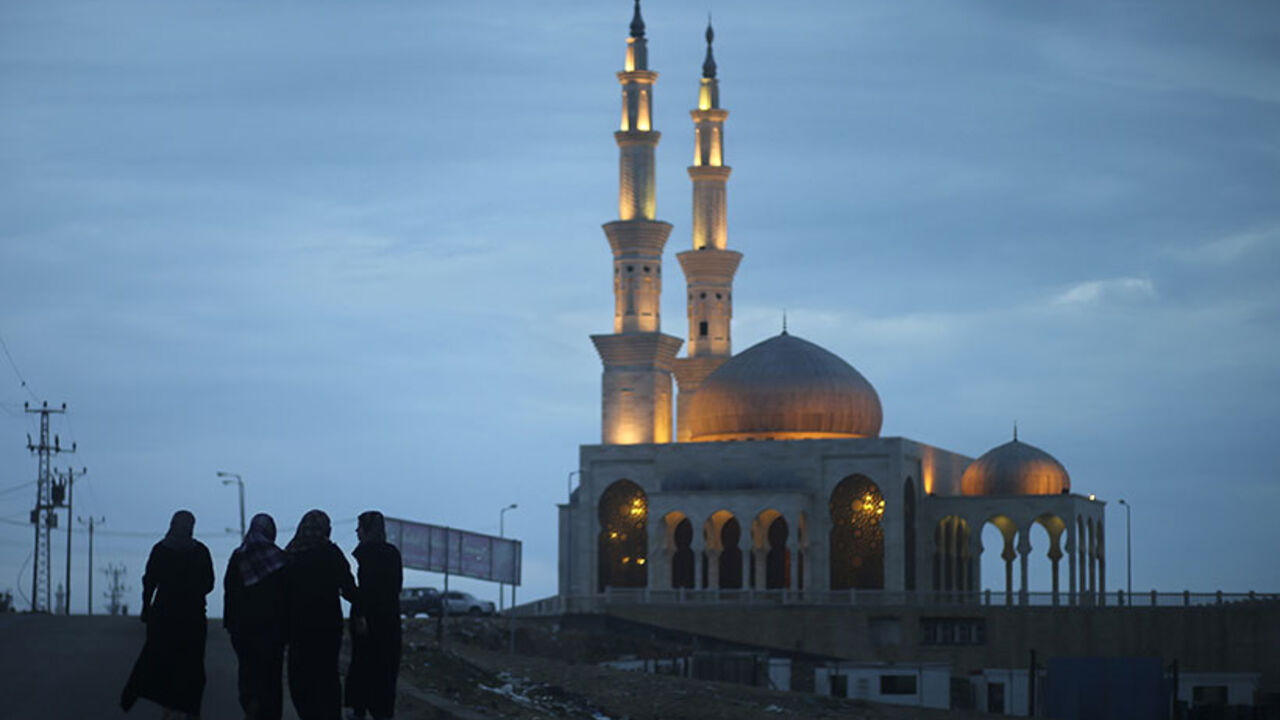 Palestinian women walk near a mosque in a street in the Gaza Strip March 13, 2014.  REUTERS/Mohammed Salem (GAZA - Tags: POLITICS SOCIETY RELIGION) - RTR3GYYE
