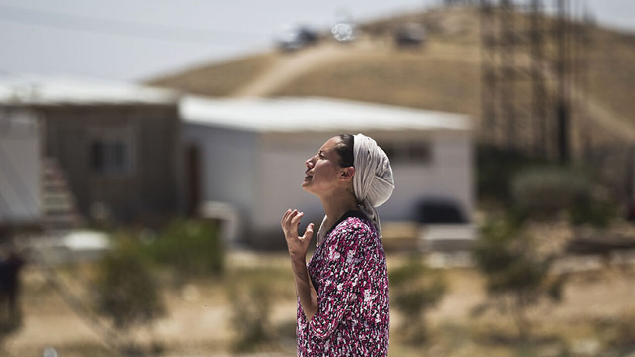 A Jewish settler reacts as she stands atop the roof of a temporary structure before Israeli policemen demolish it in the West Bank Jewish settler outpost of Maale Rehavam, near Bethlehem May 14, 2014.  Some seven structures were razed on Wednesday by Israeli border police officers and no injuries or arrests were made during the incidences, a police spokesman said on Wednesday. The structures were demolished as part of Israel's continuing effort to remove settlements built without government authorization. R