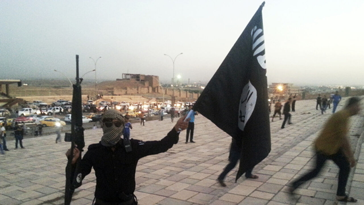 A fighter of the Islamic State of Iraq and the Levant (ISIL) holds an ISIL flag and a weapon on a street in the city of Mosul, June 23, 2014. U.S. Secretary of State John Kerry held crisis talks with leaders of Iraq's autonomous Kurdish region on Tuesday urging them to stand with Baghdad in the face of a Sunni insurgent onslaught that threatens to dismember the country. Picture taken June 23, 2014. REUTERS/Stringer (IRAQ - Tags: CIVIL UNREST POLITICS TPX IMAGES OF THE DAY) - RTR3VIB1