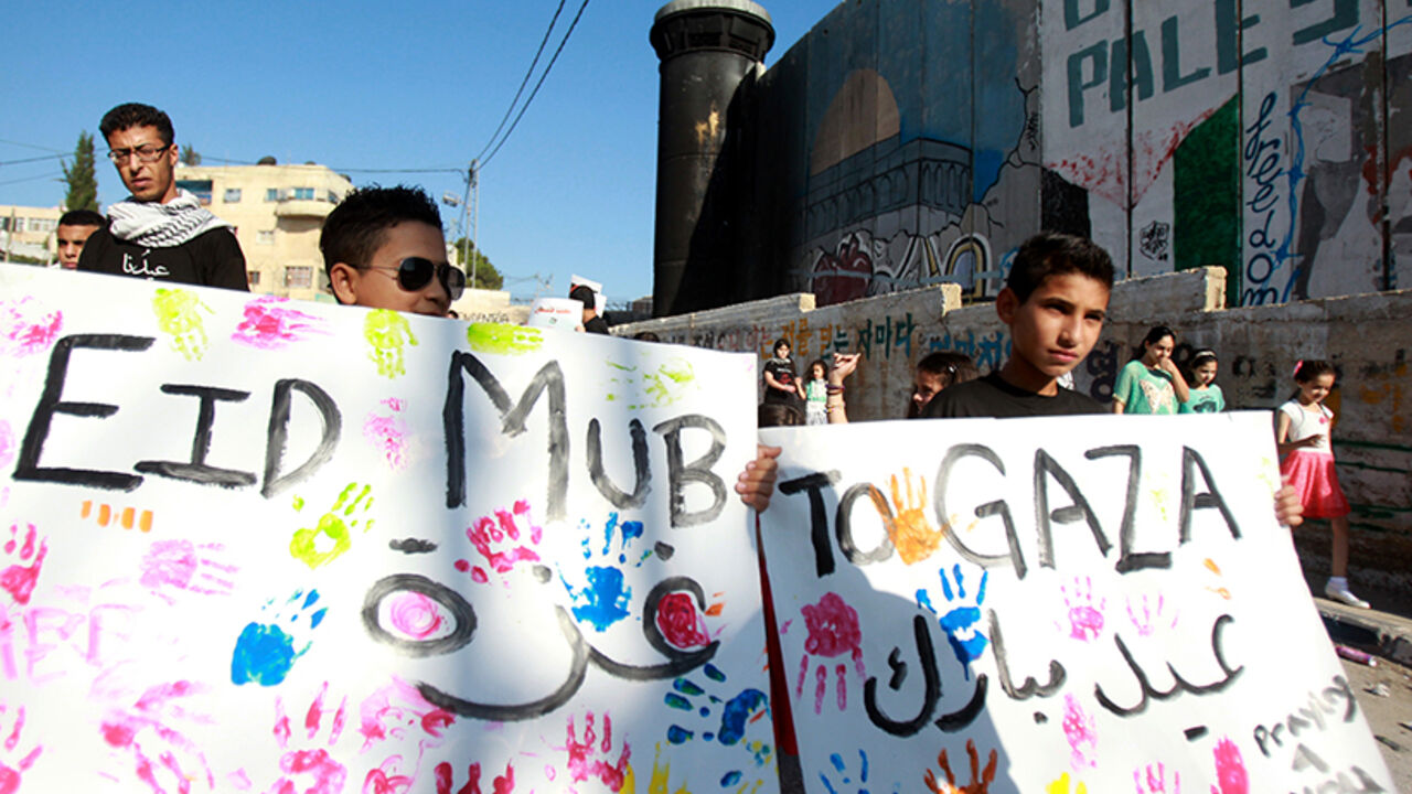 Young Palestinians hold placards reading "Eid Mubarak to Gaza" (Happy Eid to Gaza) during a demonstration in solidarity with the children killed in the ongoing Israeli devastating military assault on the Gaza Strip, on July 28, 2014, in the Aida Palestinian refugee camp near the West Bank city of Bethlehem. At least 1,032 Palestinians have died so far in the fighting as well as 43 Israeli soldiers and three Israeli civilians. The Muslim festival of Eid al-Fitr that marks the end of the holy fasting month of