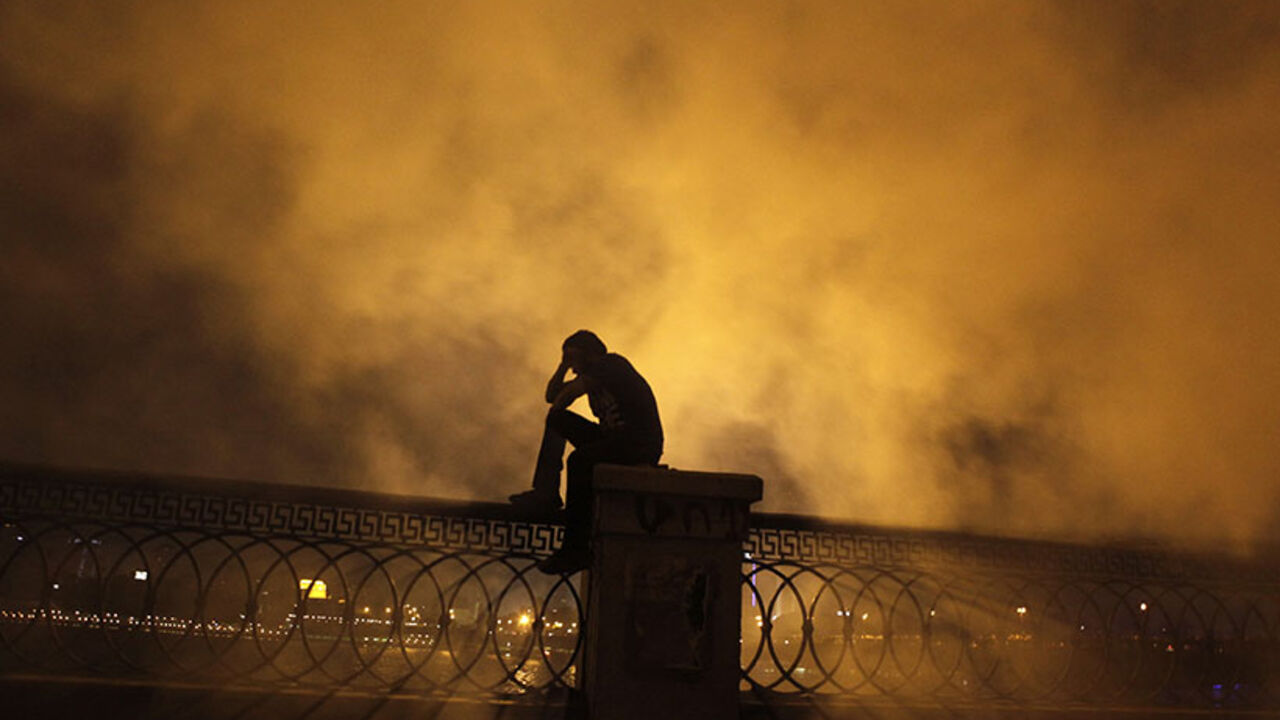 A protester covers his face as he stands in front of tear gas during clashes with riot police along a road at Kornish El Nile which leads to the U.S. embassy, near Tahrir Square in Cairo September 15, 2012. Clashes near the U.S. Embassy in central Cairo between police and Egyptians incensed over a film denigrating the Prophet Mohammad entered their fourth day early on Saturday, leaving one protester dead and dozens more injured.  REUTERS/Amr Abdallah Dalsh  (EGYPT - Tags: POLITICS CIVIL UNREST RELIGION) - R