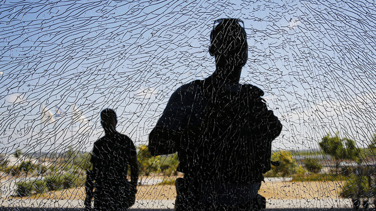 Israeli security personnel look at a window damaged by shrapnel after a short-range rocket landed on Tuesday near the Erez crossing July 16, 2014. An Israeli civilian was killed by the rocket fired from the Gaza Strip on Tuesday, the military said, the first Israeli fatality in more than a week of fighting with Palestinian militants. The Islamist group Hamas that rules Gaza claimed responsibility for launching the short-range rocket that struck an area along the border with Gaza. REUTERS/Finbarr O'Reilly (I