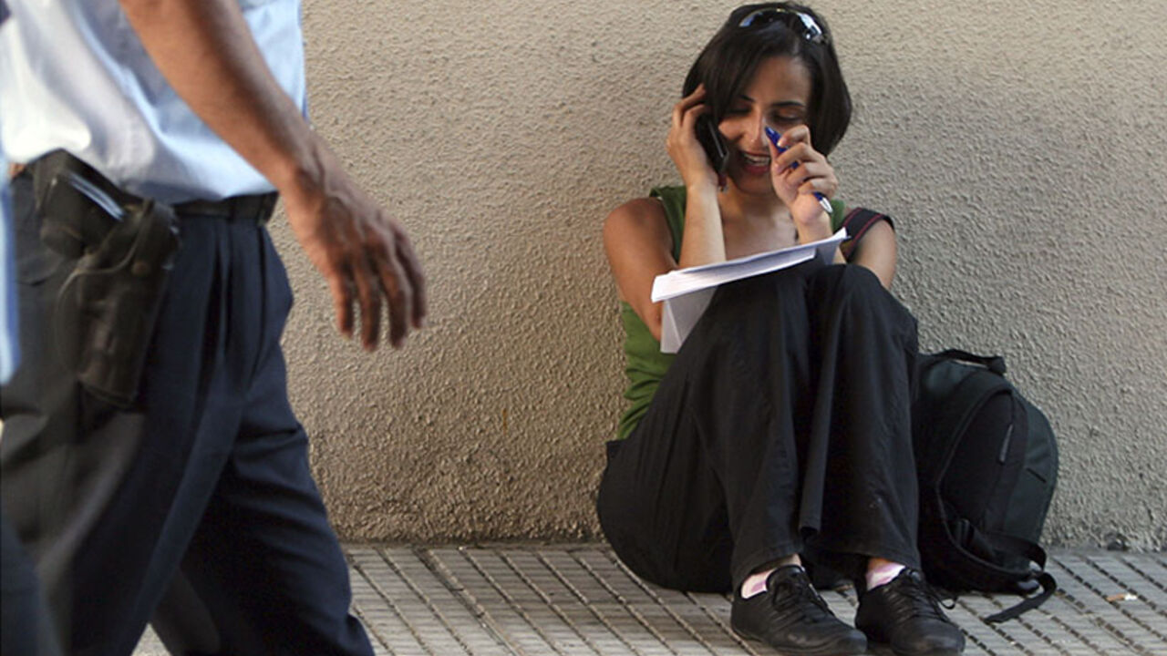 A police officer walks past a reporter talking on her mobile phone outside a Turkish court house where the trial of suspects charged with killing Turkish-Armenian editor Hrant Dink is held in Istanbul July 2, 2007.  Eighteen suspects went on trial on Monday for the murder of ethnic Armenian editor Dink in a case seen as a litmus test for the rule of law and the right to free speech in Turkey, a European Union candidate country. REUTERS/Fatih Saribas (TURKEY) - RTR1RDTQ