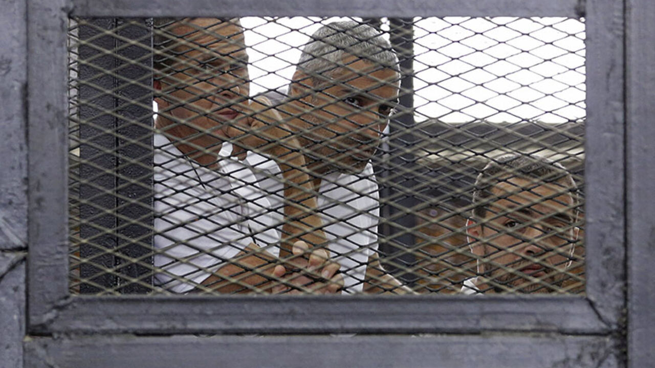 Al Jazeera journalists (L-R) Peter Greste, Mohammed Fahmy and Baher Mohamed stand behind bars at a court in Cairo June 1, 2014. The trial of the three Al Jazeera journalists accused of aiding of a "terrorist organisation" has been postponed to June 6. The Qatar-based television network's journalists - Peter Greste, an Australian, Mohamed Fahmy, a Canadian-Egyptian national, and Baher Mohamed, an Egyptian - were detained in Cairo on December 29. All three have denied the charges, with Al Jazeera saying the a