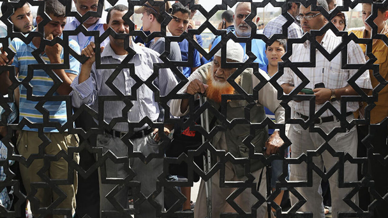 People, hoping to cross into Egypt, stand behind a gate as they wait at the Rafah crossing between Egypt and the southern Gaza Strip  August 5, 2014. Israel pulled its ground forces out of the Gaza Strip on Tuesday and began a 72-hour truce with Hamas mediated by Egypt as a first step towards negotiations on a more enduring end to the month-old war. Gaza officials say the war has killed 1,834 Palestinians, most of them civilians. Israel says 64 of its soldiers and three civilians have been killed since figh